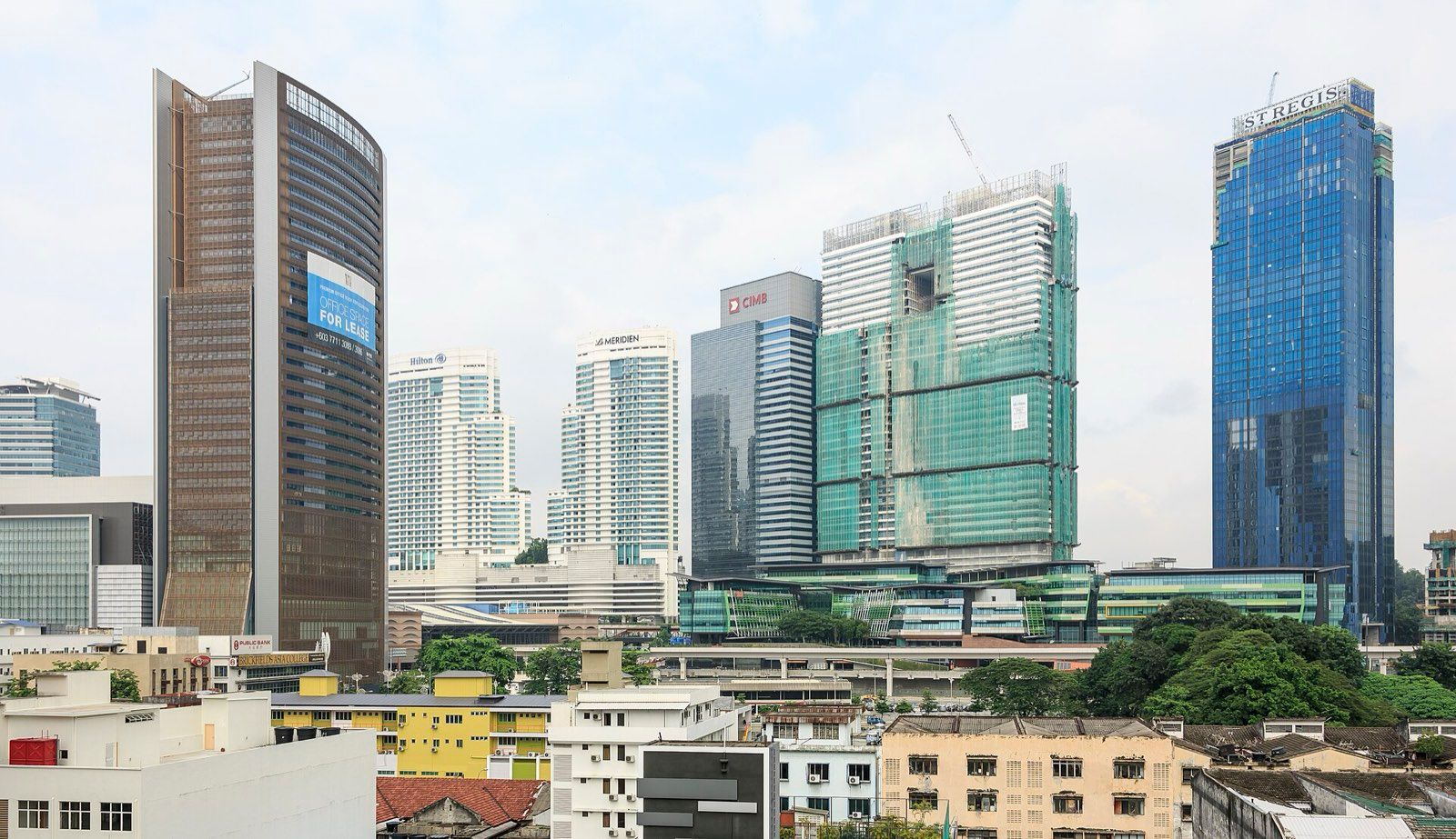Office and hotel towers around KL Sentral station in Kuala Lumpur, with older low-rise buildings in the foreground and one tower under construction